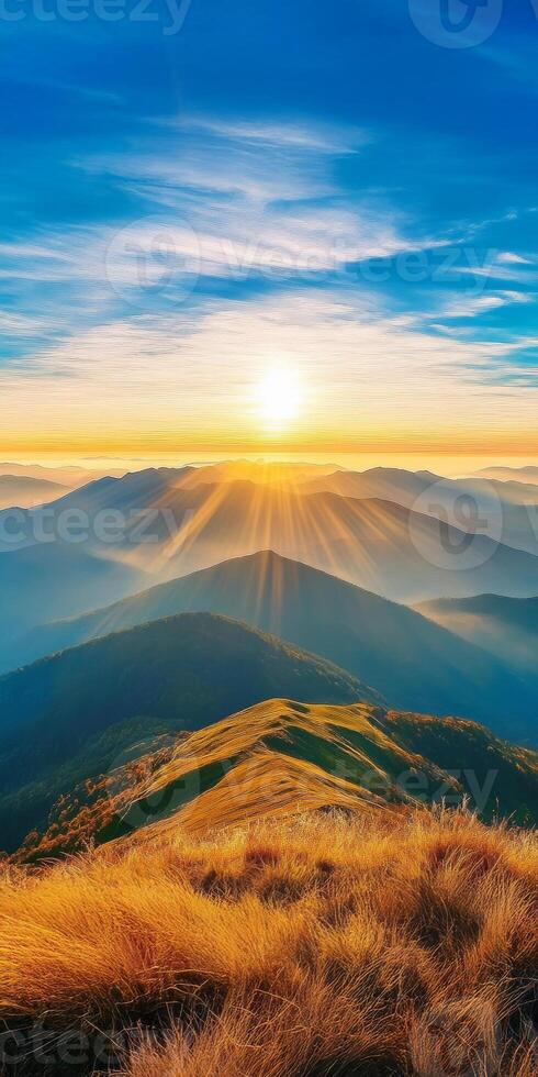 breathtaking sunrise over rolling mountains, with golden rays illuminating landscape and soft grass in foreground, creating serene and peaceful atmosphere photo