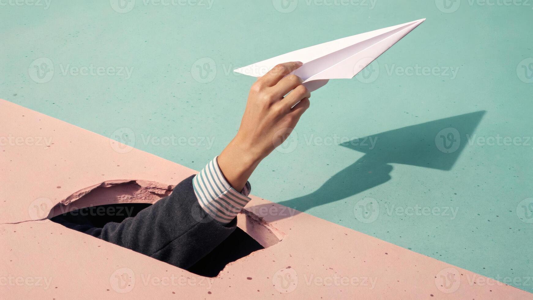 Hand Holding Paper Plane Through Wall in Surreal Concept photo
