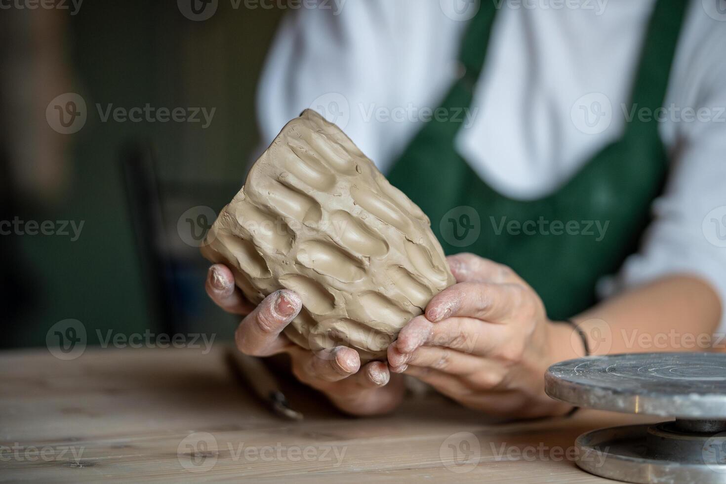 Molding craft ceramics. table in pottery studio with female artist shaping wet clay for potter bow photo