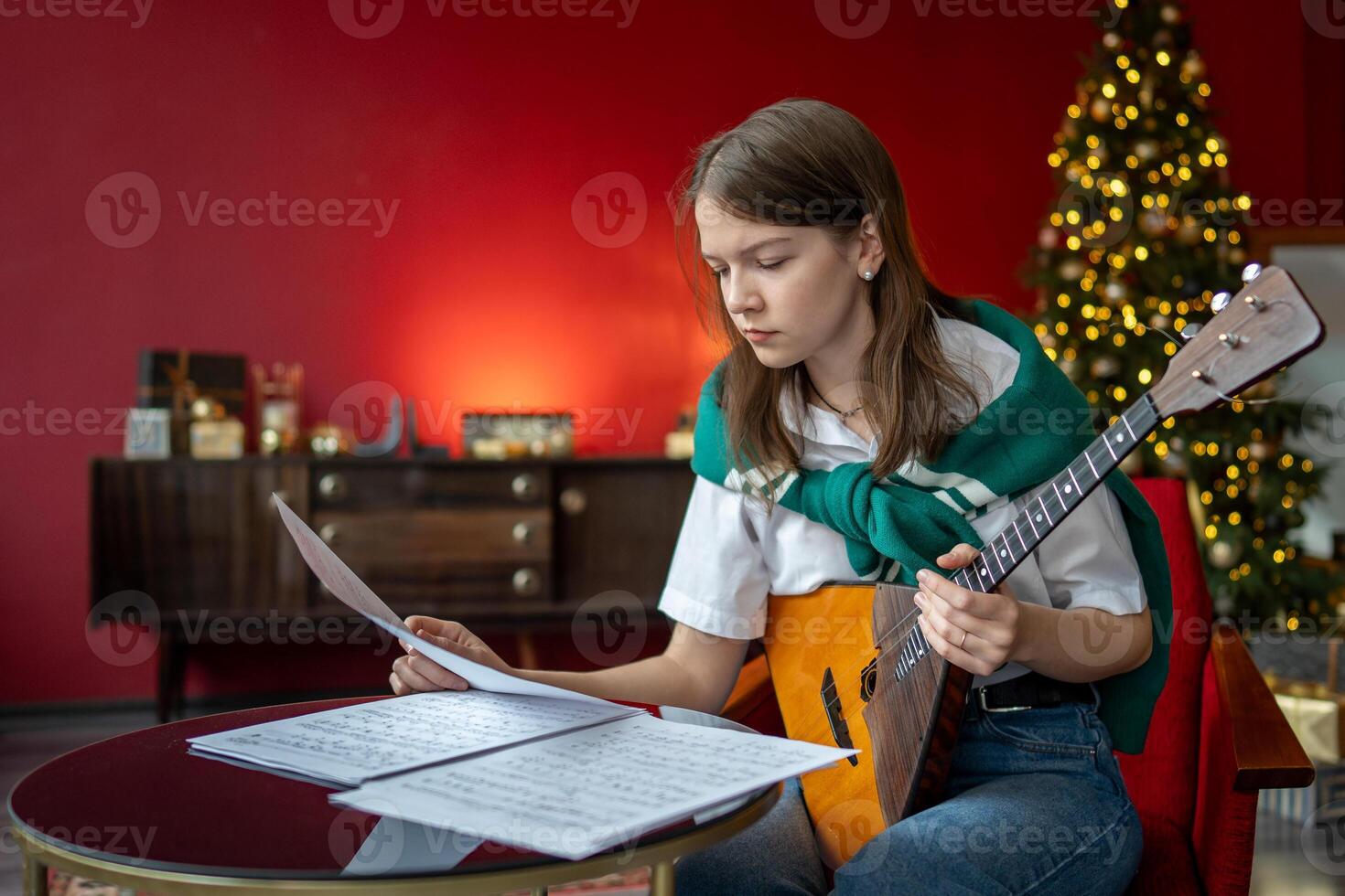 Focused woman studies balalaika song, read sheet music. Christmas event preparation, song homework photo