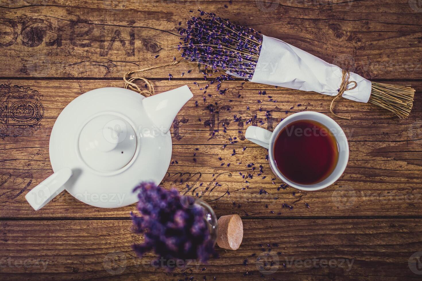 Bunch of dry cut lavender, cup of tea and teapot on wooden table. Top view. photo