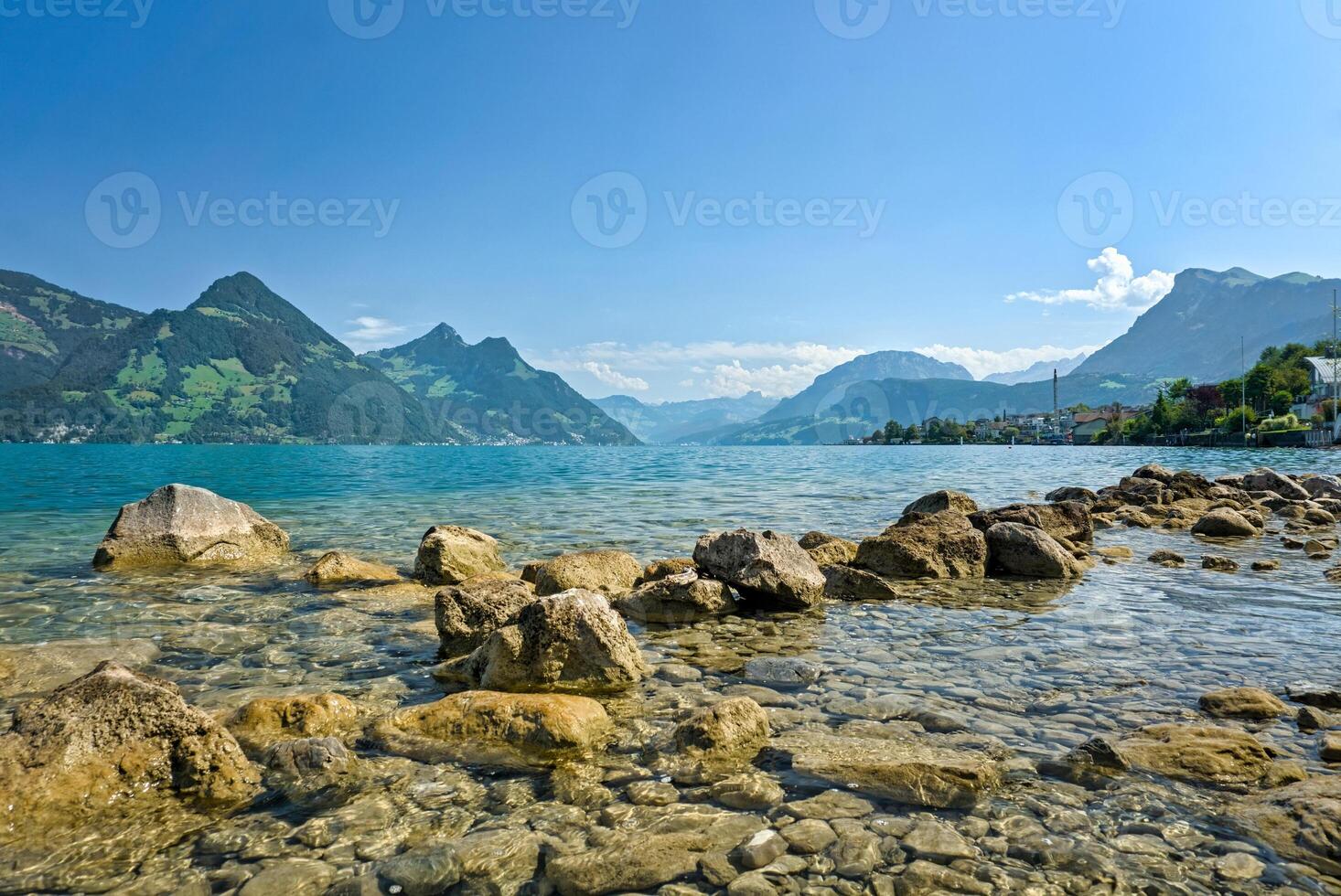 A stunning view over Lake Vierwaldstaetter on a beautiful summer day, where the calm waters reflect the surrounding Swiss Alps under a clear blue sky. photo