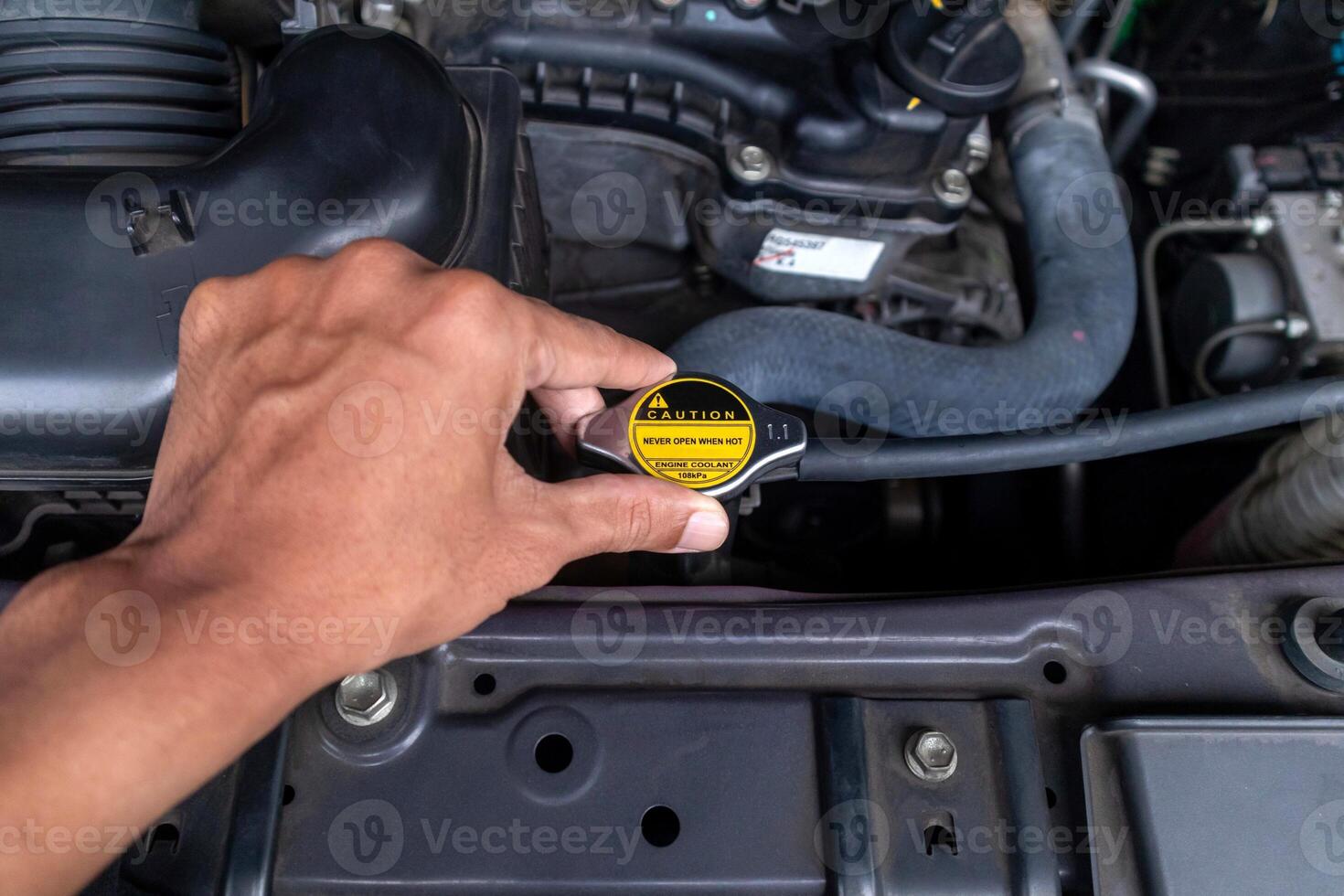 A mechanic's hand holding the radiator cap and checking the car radiator water. photo