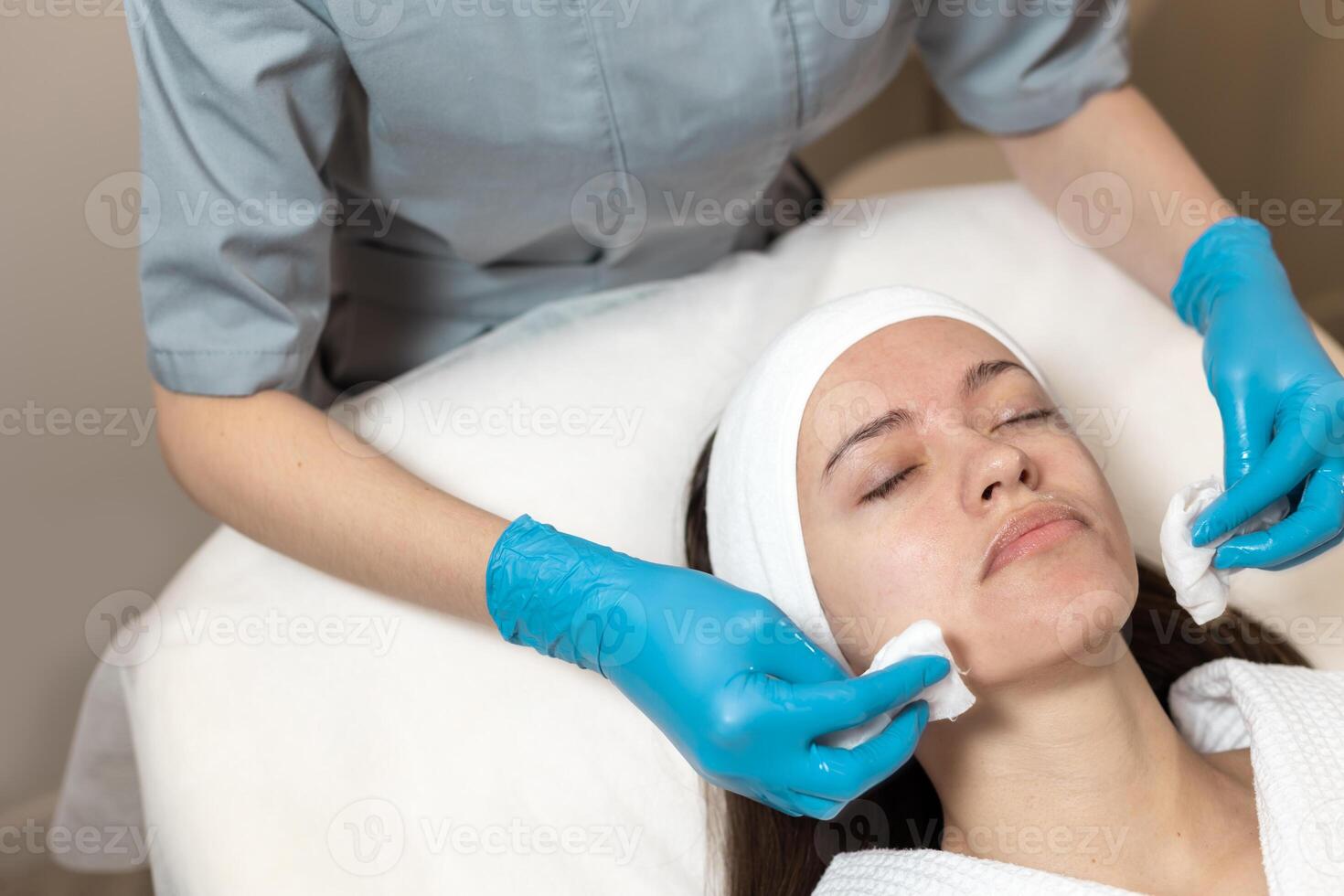 Skincare professional applying treatment to woman's face during facial session in spa environment photo