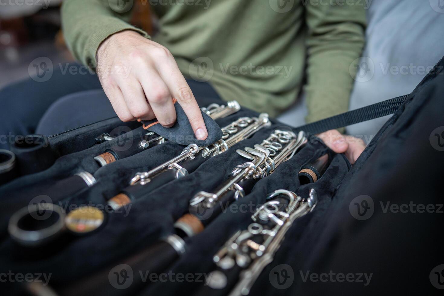 Careful hands clean clarinet with soft cloth, removing traces of use while instrument rests in case photo