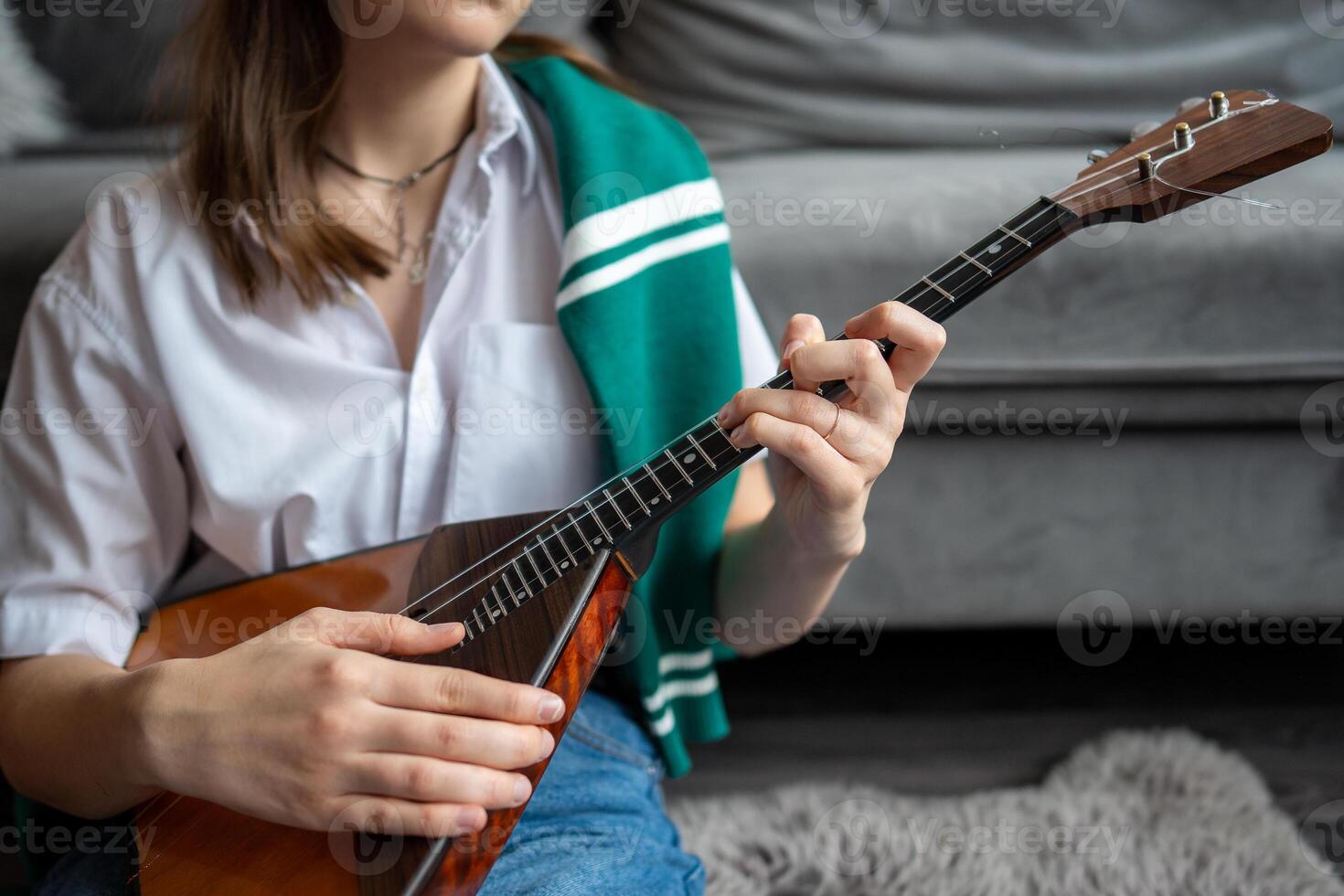 Woman musicians hands pick up notes and learn chords on balalaika at home. Fingerstyle technique photo