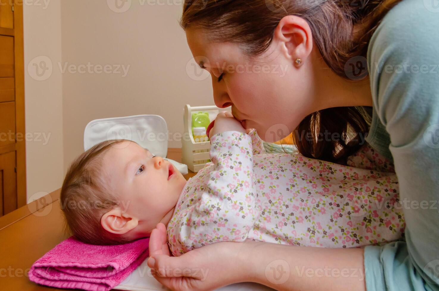 Mother kissing hands of her baby lying photo