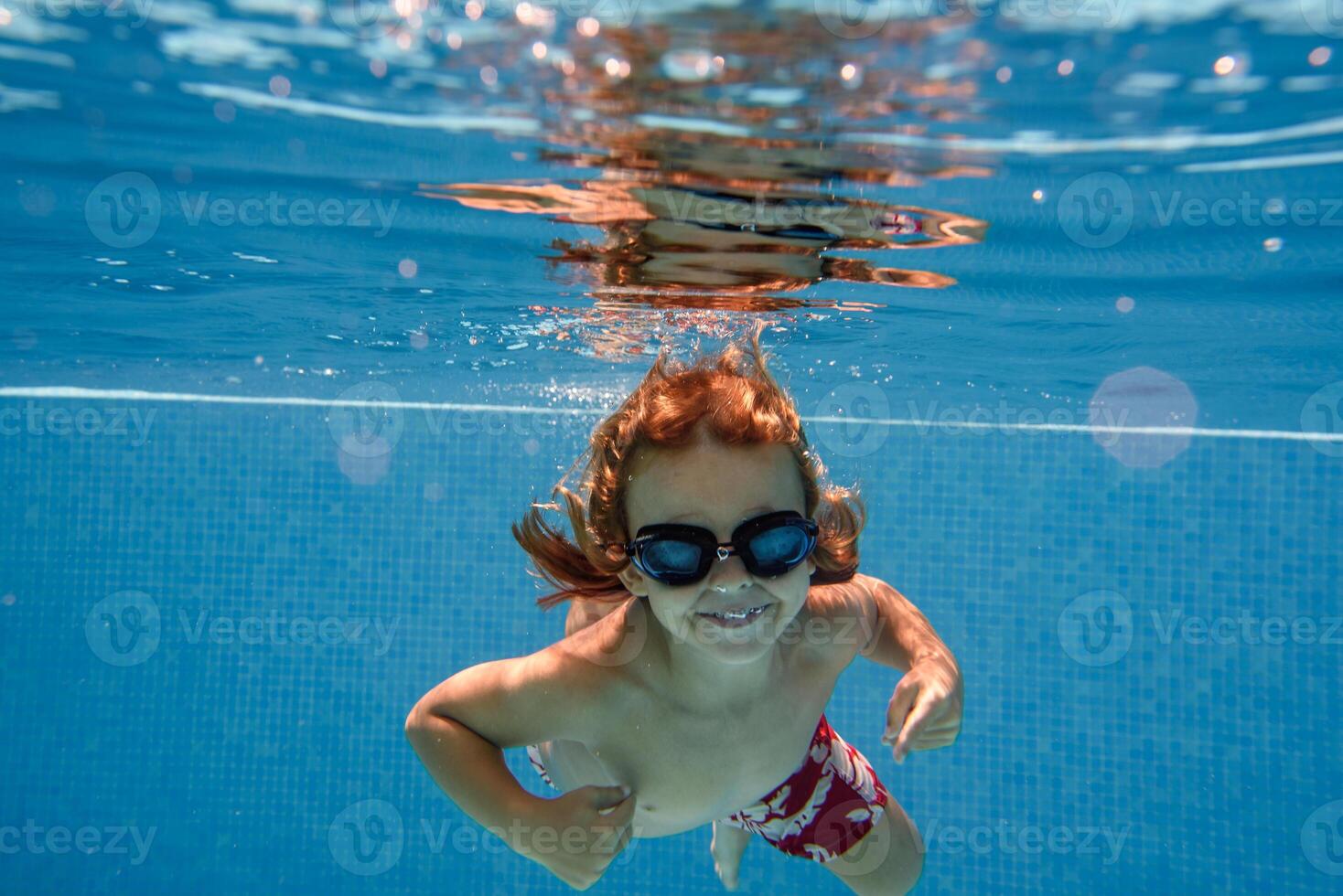 Excited boy in goggles swimming in pool photo