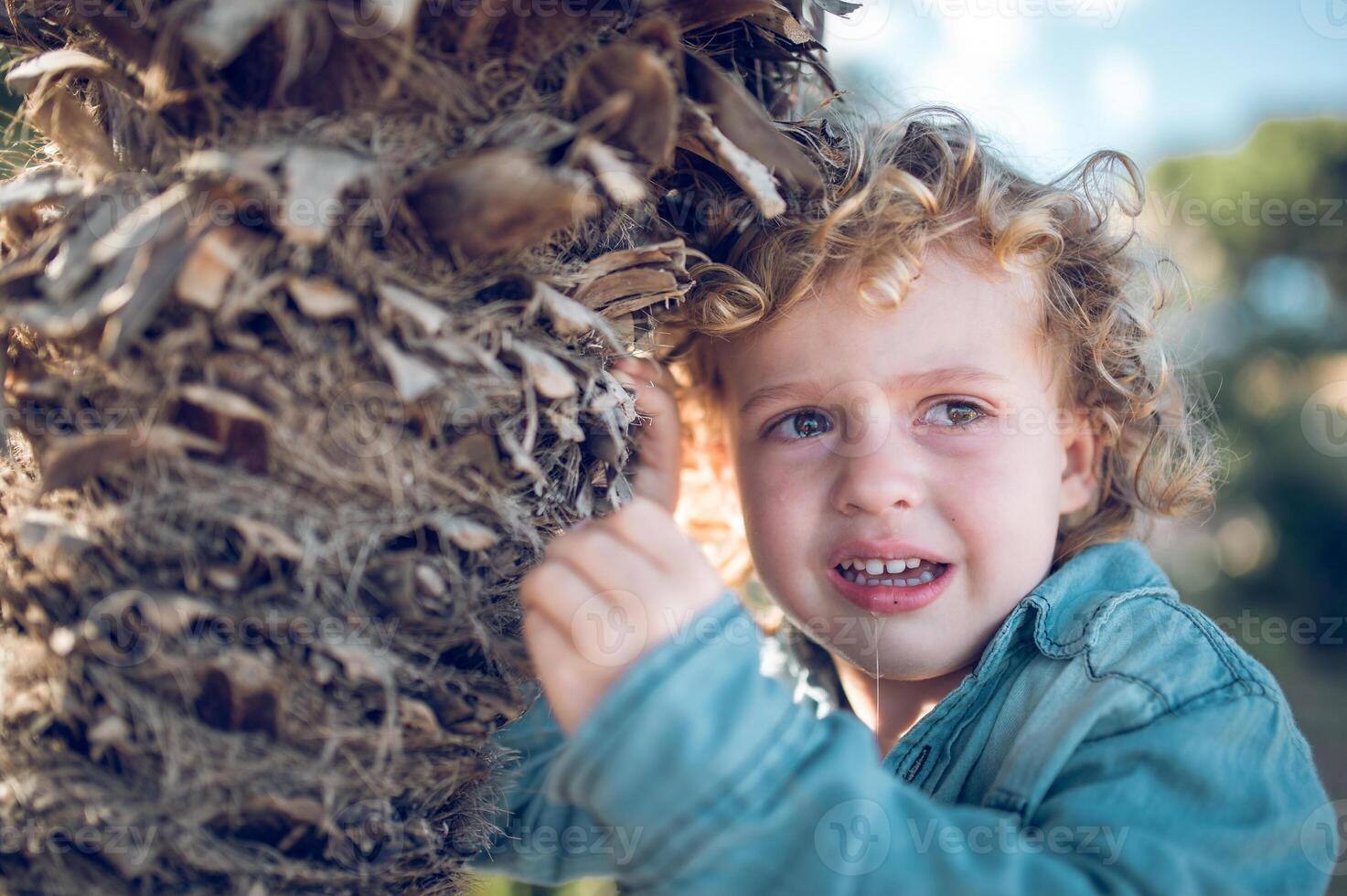 Crying boy near tree trunk photo