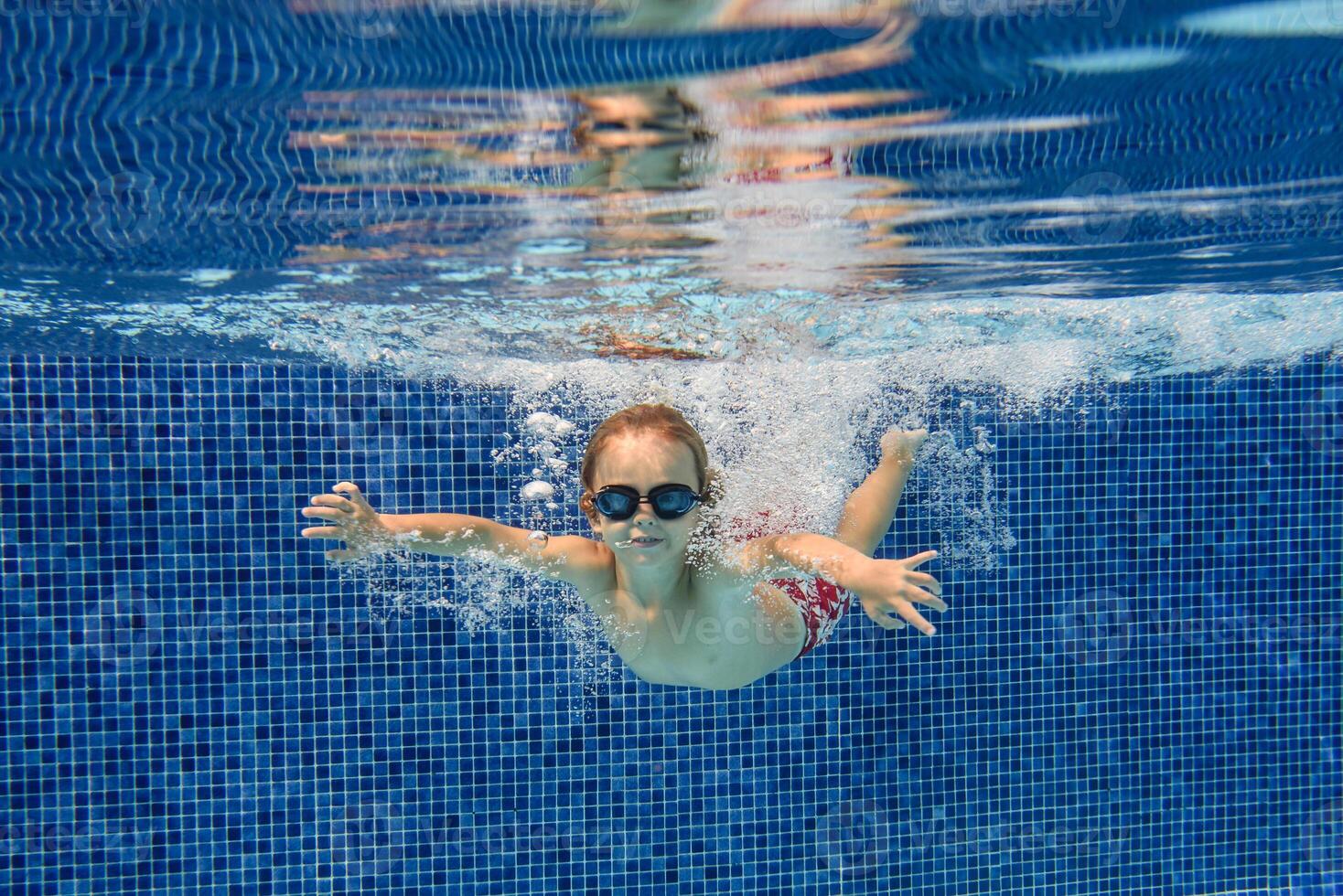 Active boy swimming in clear pool water photo