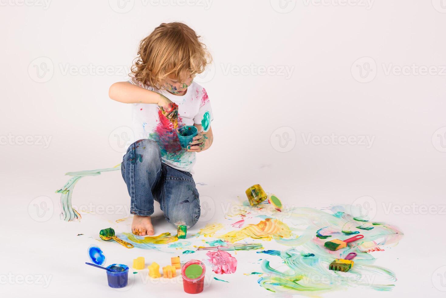 Boy smearing paints on floor photo