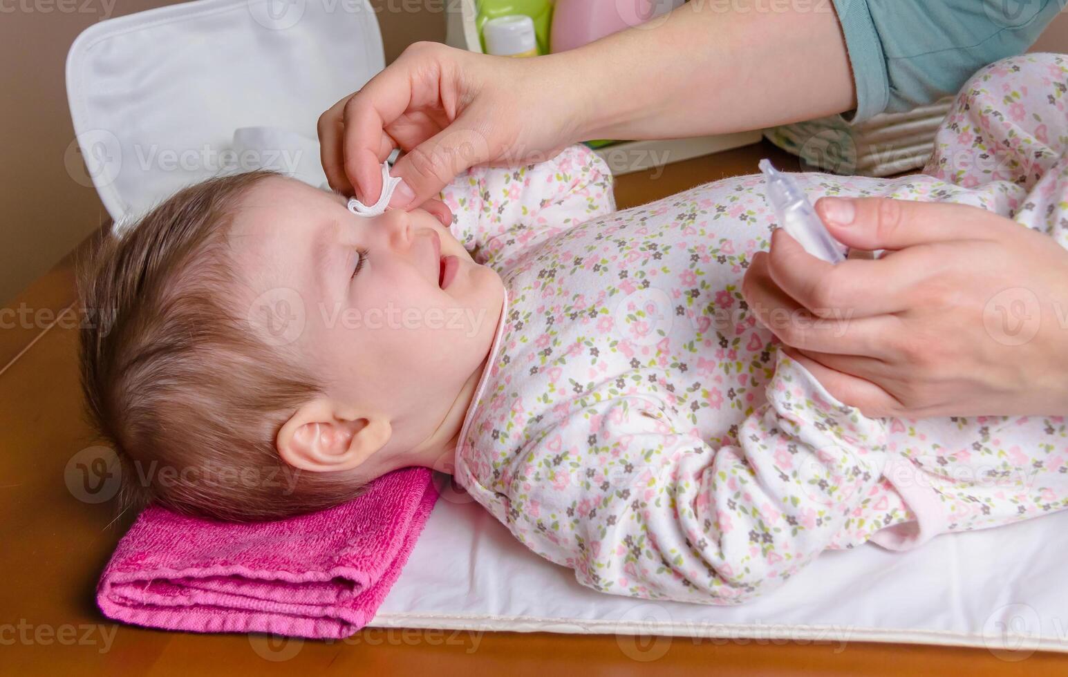 Mother hands cleaning eyes of baby with cotton photo
