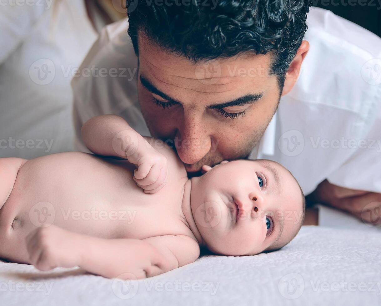 Man kissing to peaceful newborn lying over bed photo