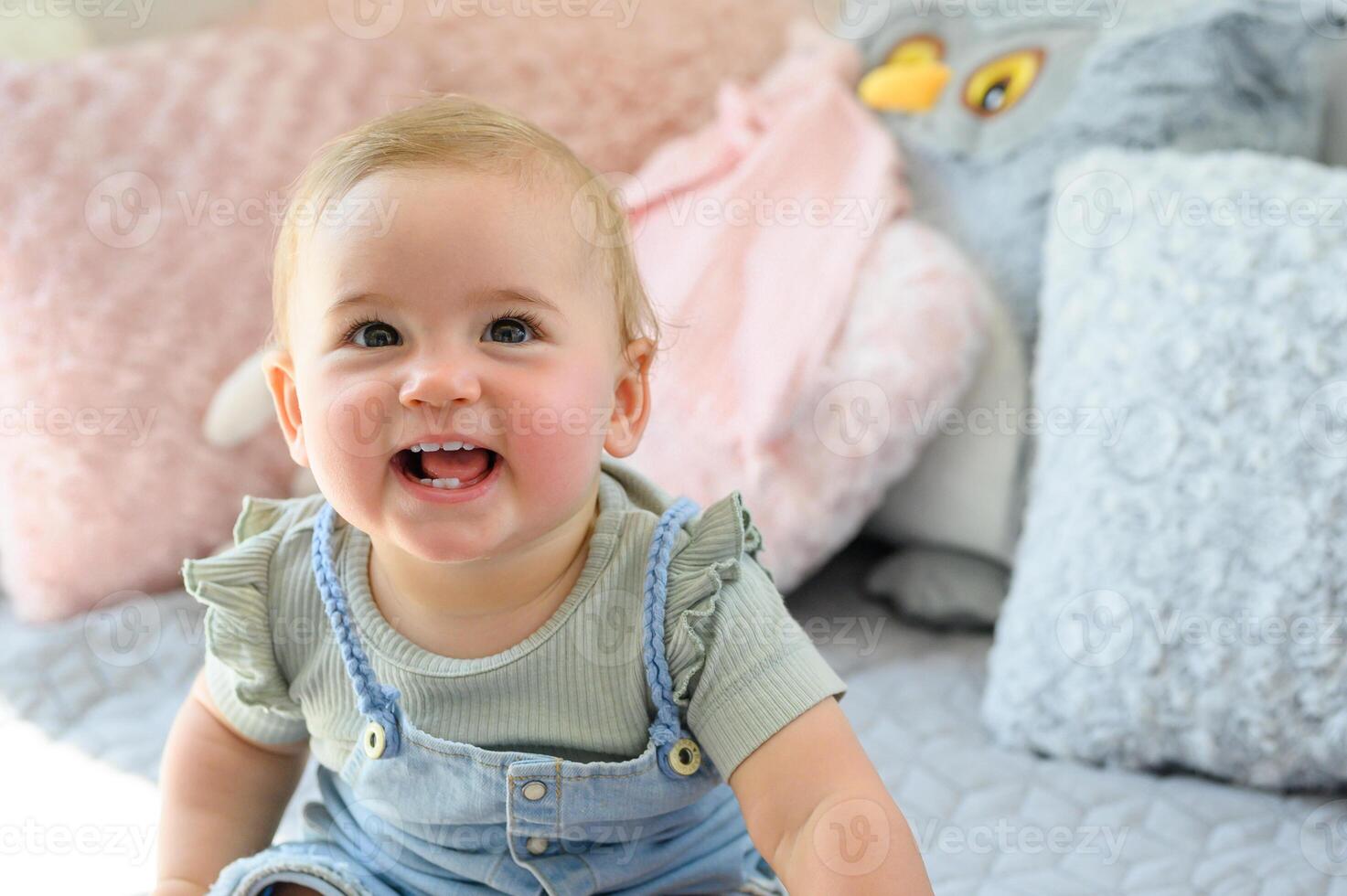 Cheerful little toddler sitting on soft bed looking at camera photo