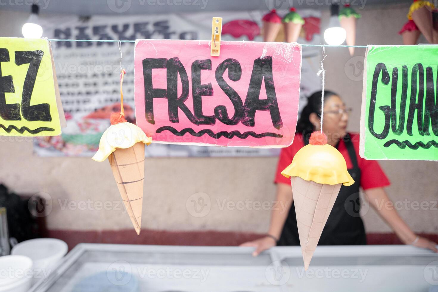 Nut and strawberry flavor signs in an ice cream street market stall with an Hispanic woman in the background photo