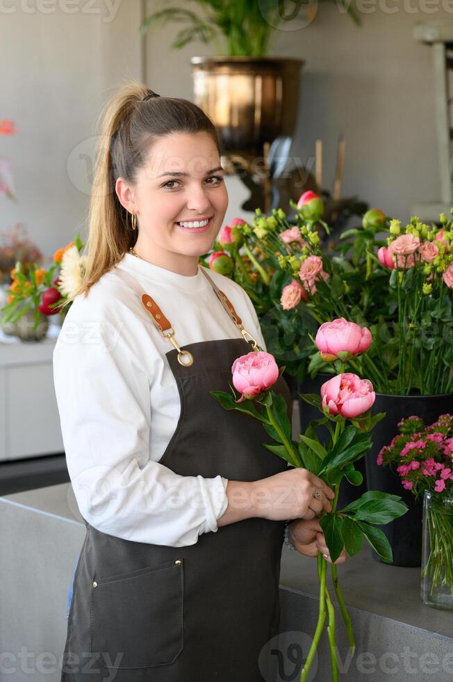Happy owner with bouquet of flowers in shop photo