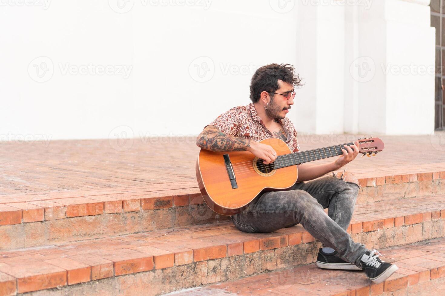 Street musician playing guitar on a staircase in the street photo