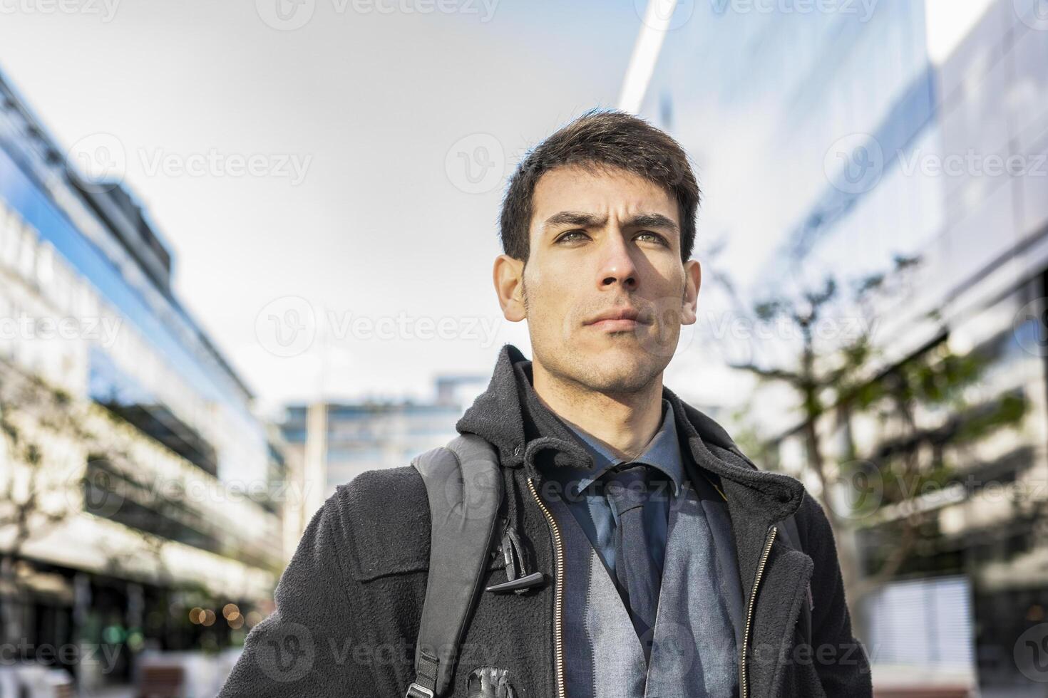 Low-angle view of an attractive businessman with his backpack on looking away while walking from his office photo