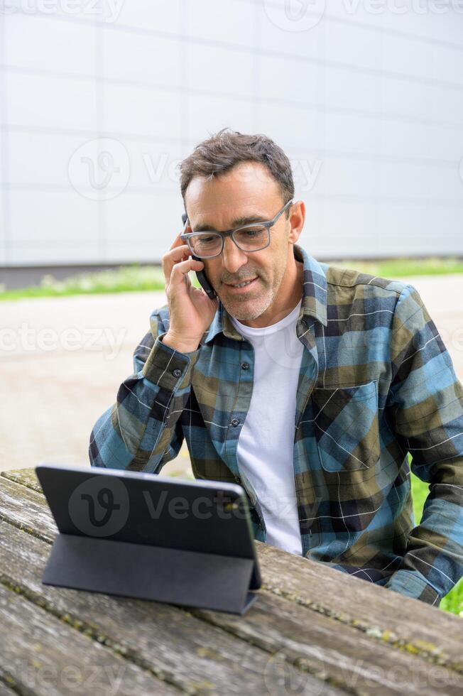Smiling man talking on phone and using laptop photo