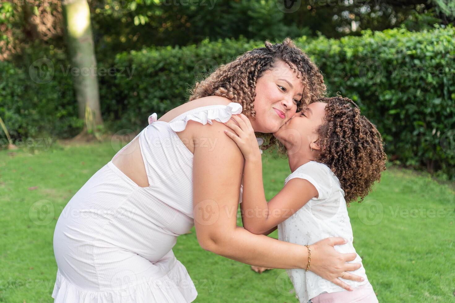 A girl kisses her mother on the cheek in the open air photo