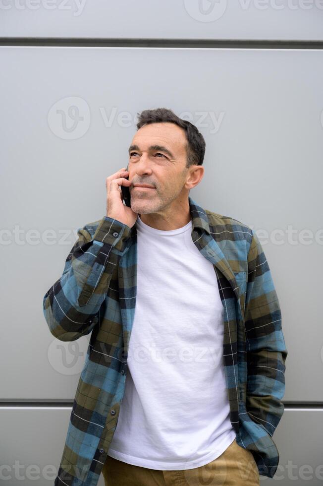 Smiling man talking on smartphone and looking away photo