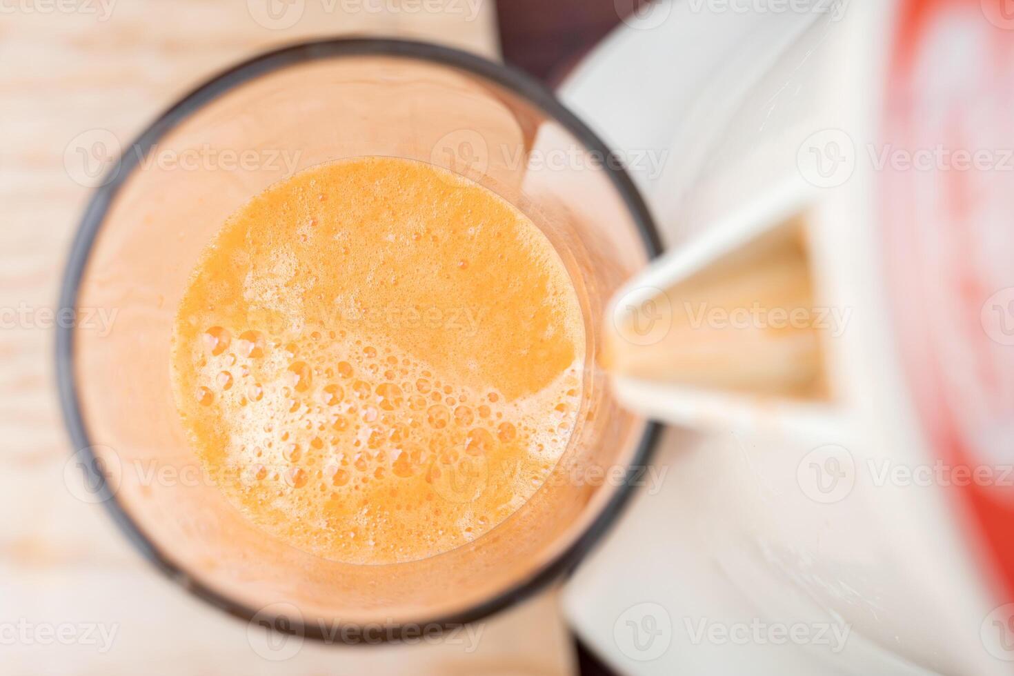 Close up of the bubbles of a fresh carrot juice being filled from a traditional squeezer. photo