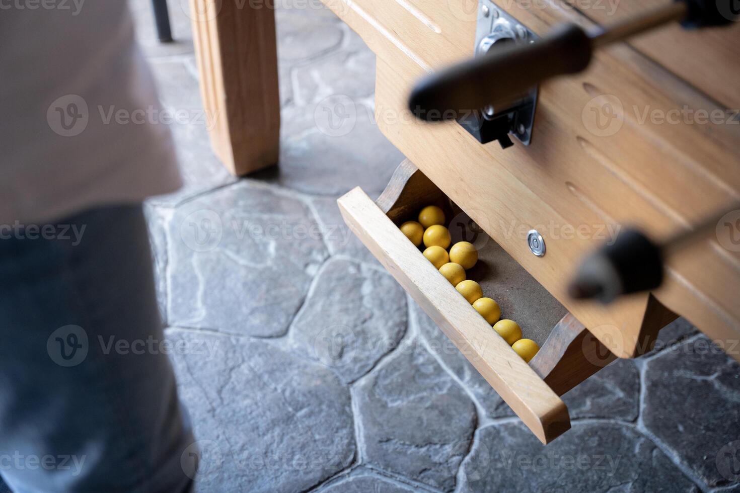 Close up of some yellow table football balls ready to be played in the dispenser photo