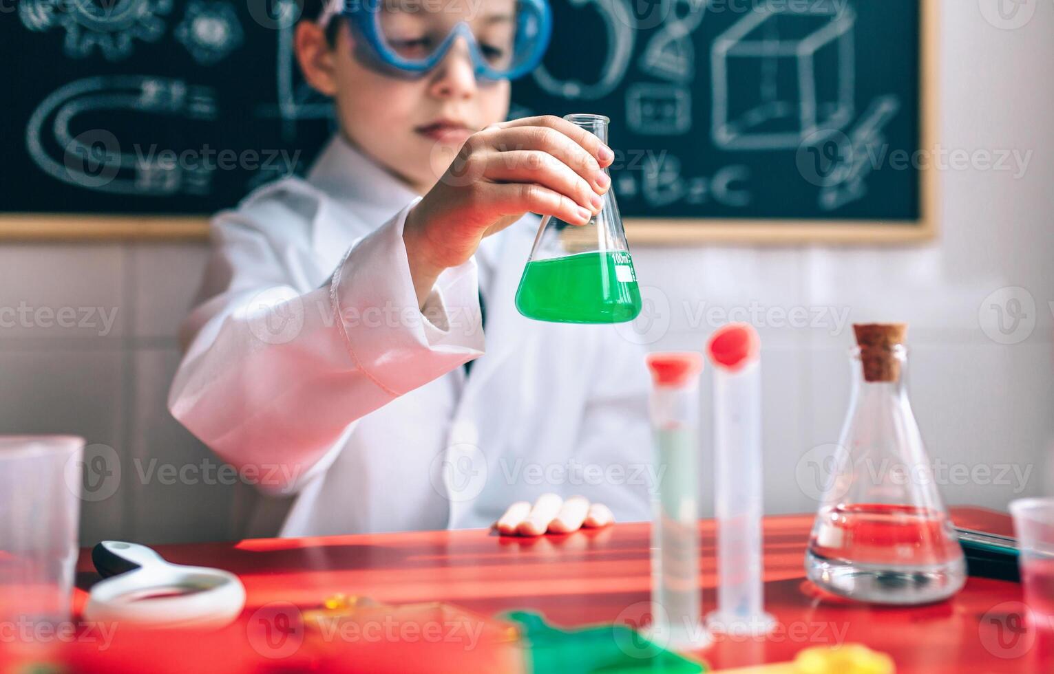 Serious boy holding flask with chemical liquid photo