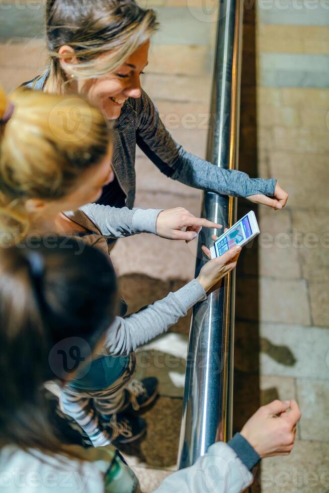Top view of smiling women runners friends looking training route map on tracker cellphone app. photo