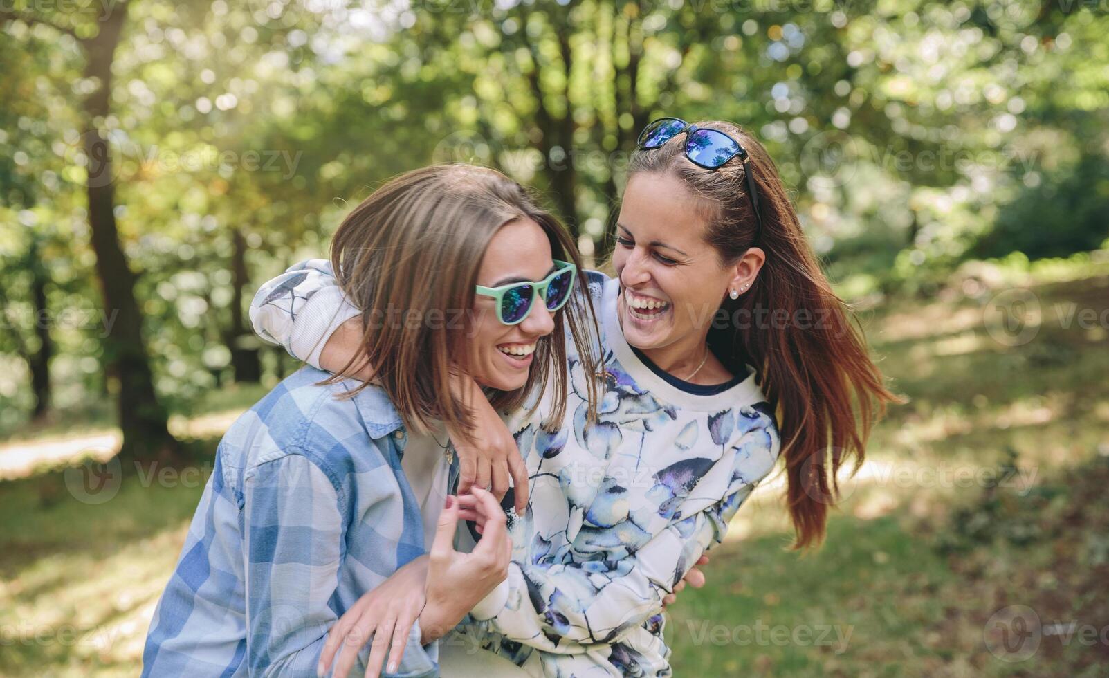 Happy women embracing and laughing over nature background photo