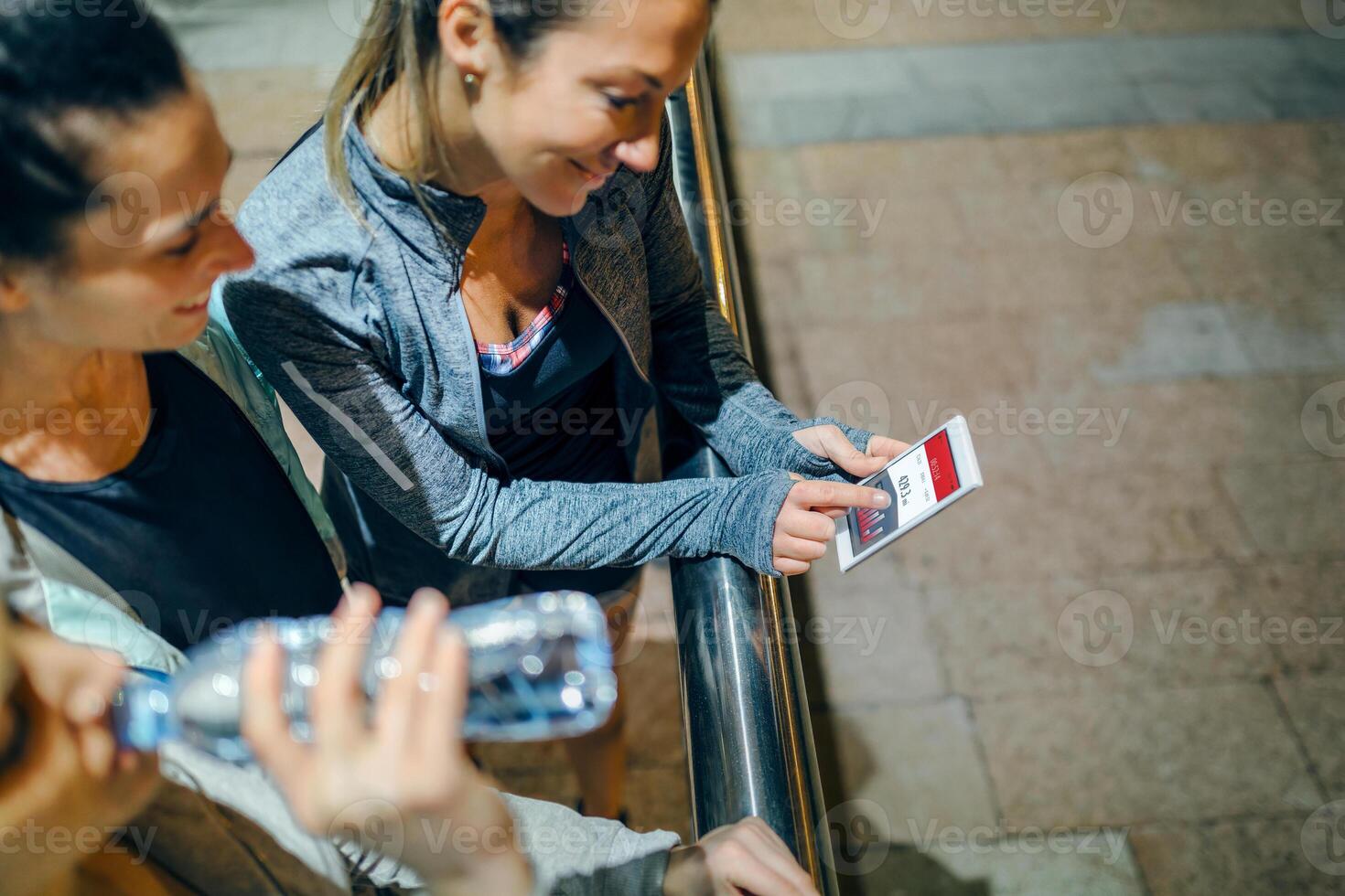 Top view of happy women runners friends checking her activity summary on tracker mobile phone app photo