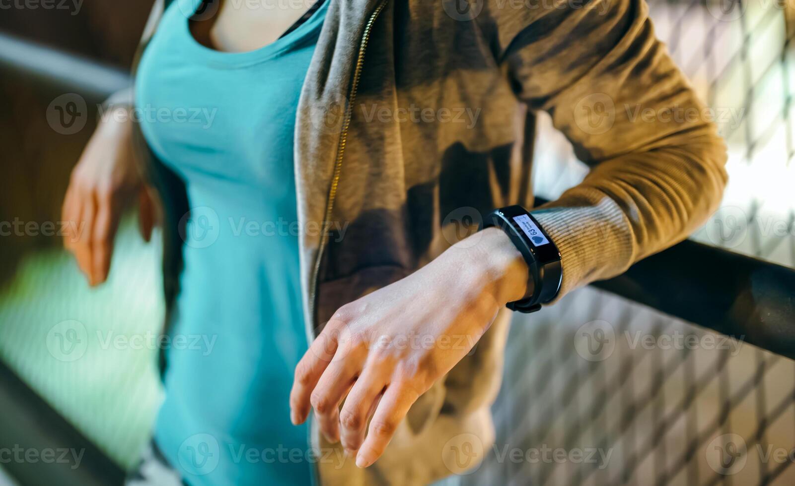 Unrecognizable female wearing digital wrist band on her hand with heart rate monitor on the screen photo