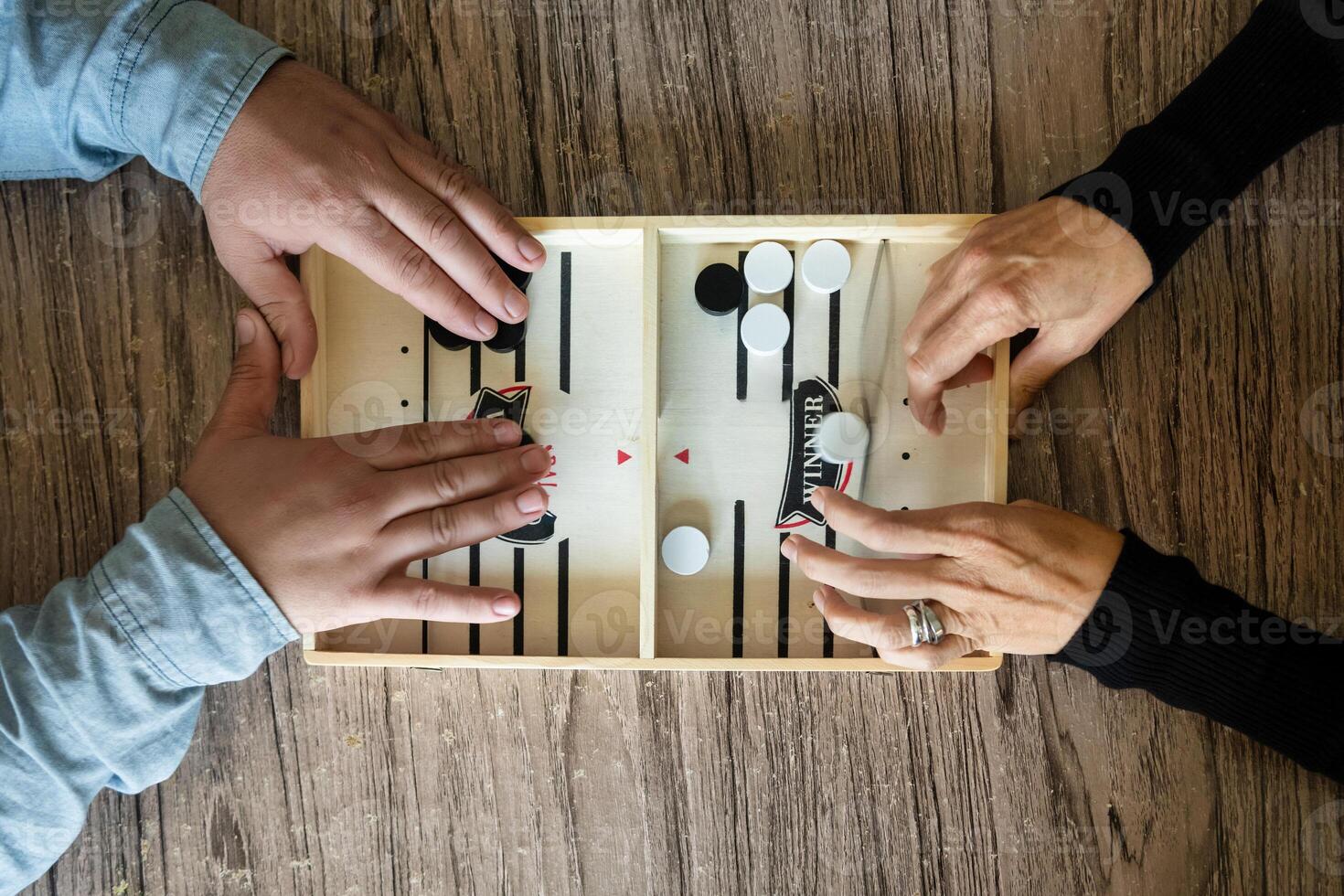 Unrecognizable people playing fast sling puck game on wooden board photo
