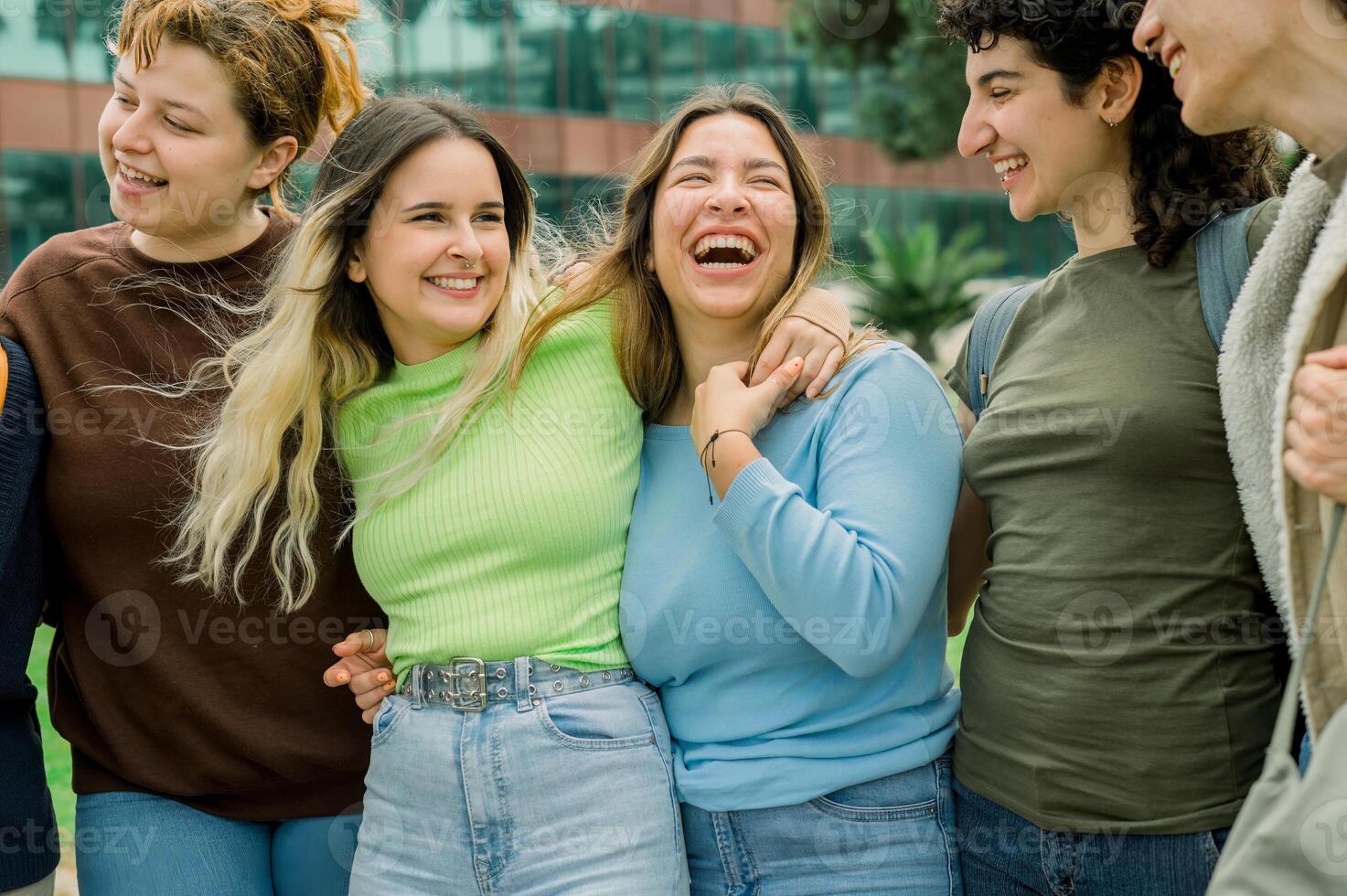 Group of diverse student friends hugging and laughing photo