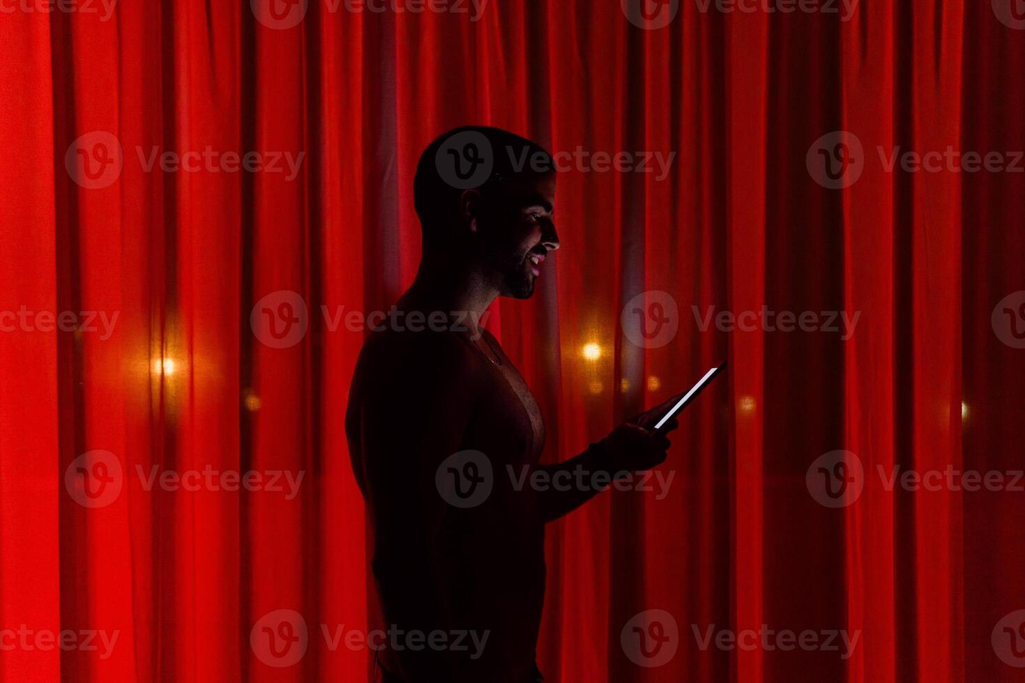Cheerful man browsing smartphone in darkness photo