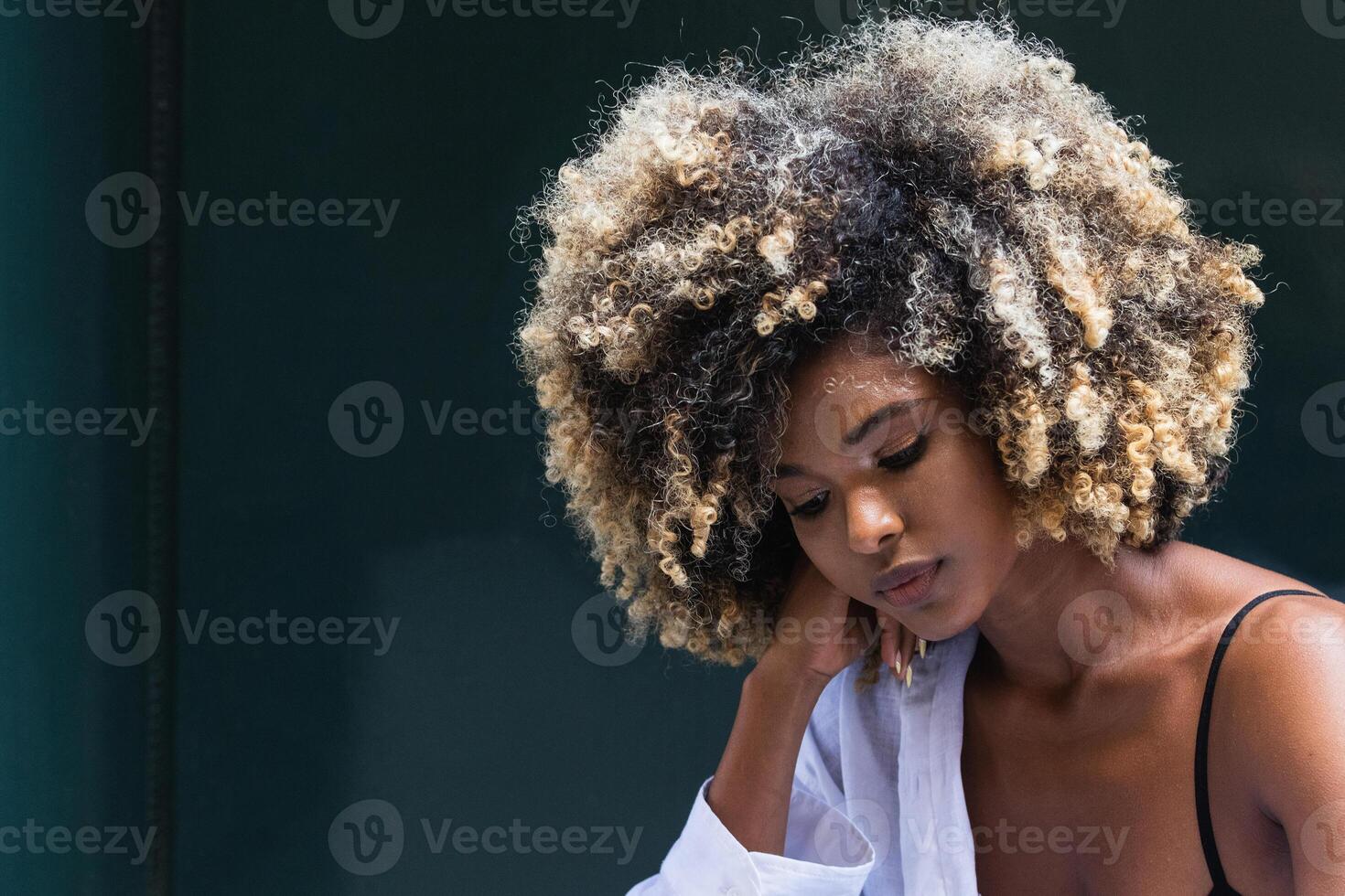 Pensive stylish black woman standing near colorful door photo