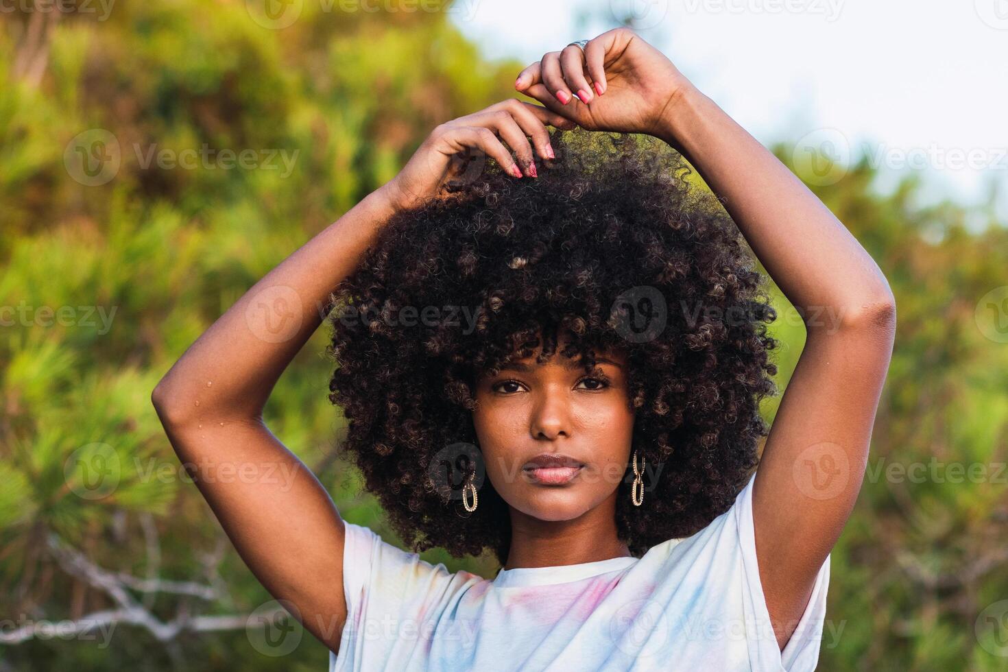 Calm black woman with Afro hairstyle in nature photo