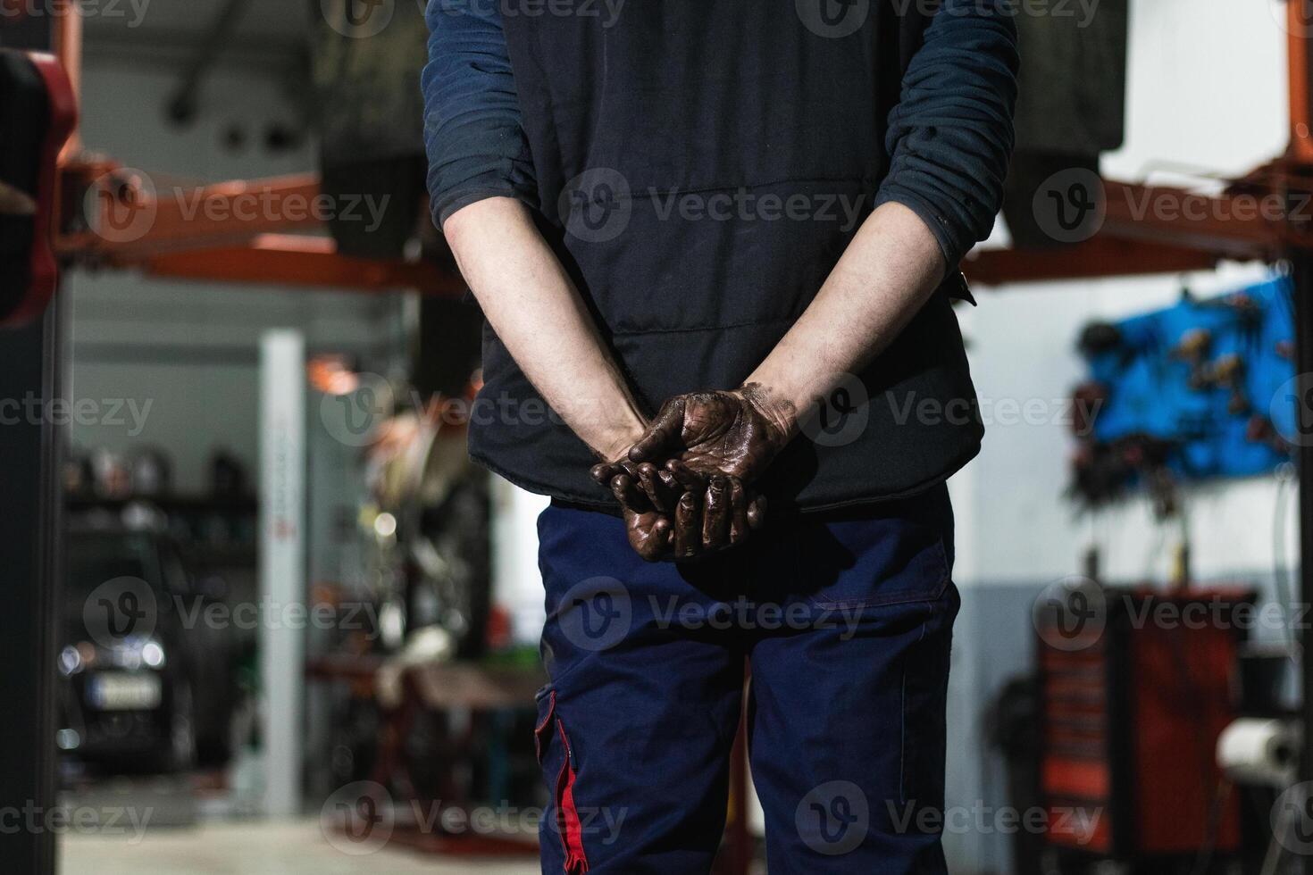 Anonymous mechanic with dirty hands behind back photo