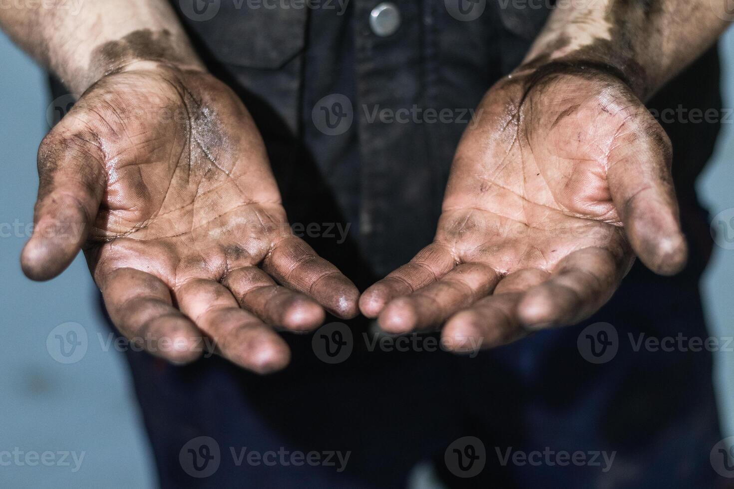 Mechanic showing dirty hands in car workshop photo
