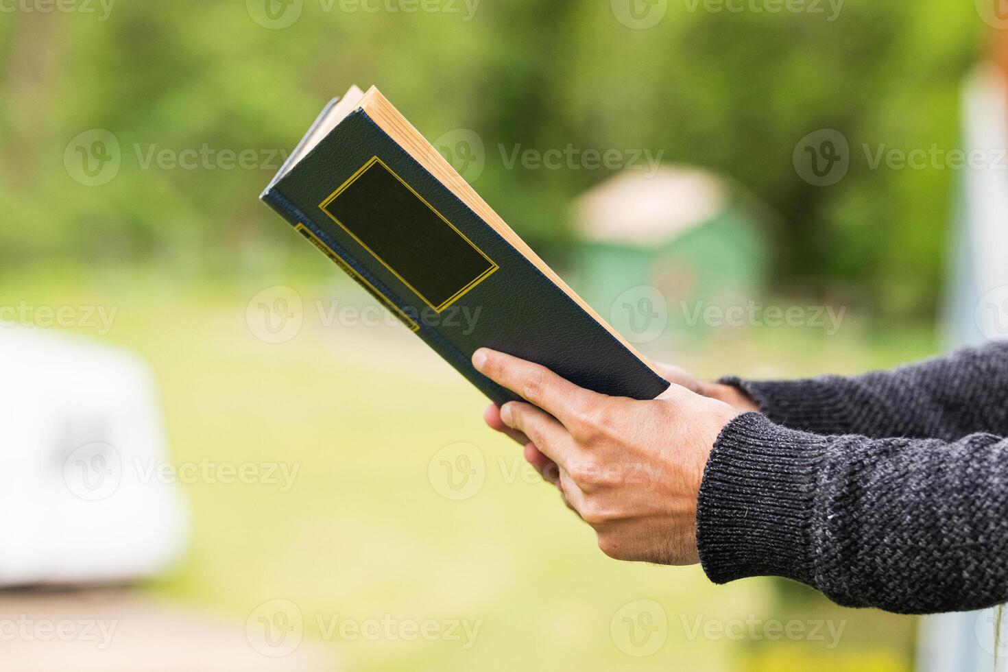 Cropped anonymous man reading book on terrace of house photo