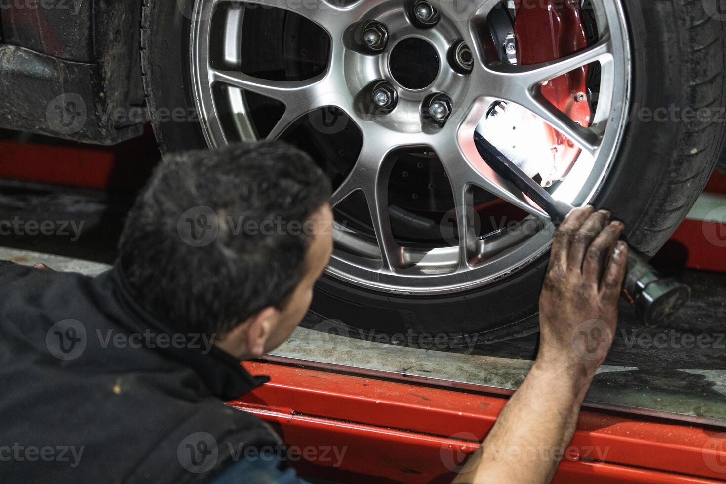 Anonymous male mechanic checking vehicle wheel in auto repair service photo