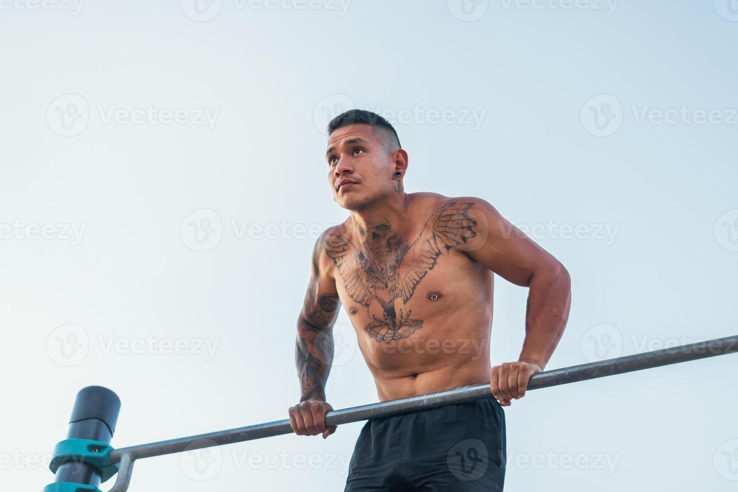 male athlete doing dips on a bar outdoors photo