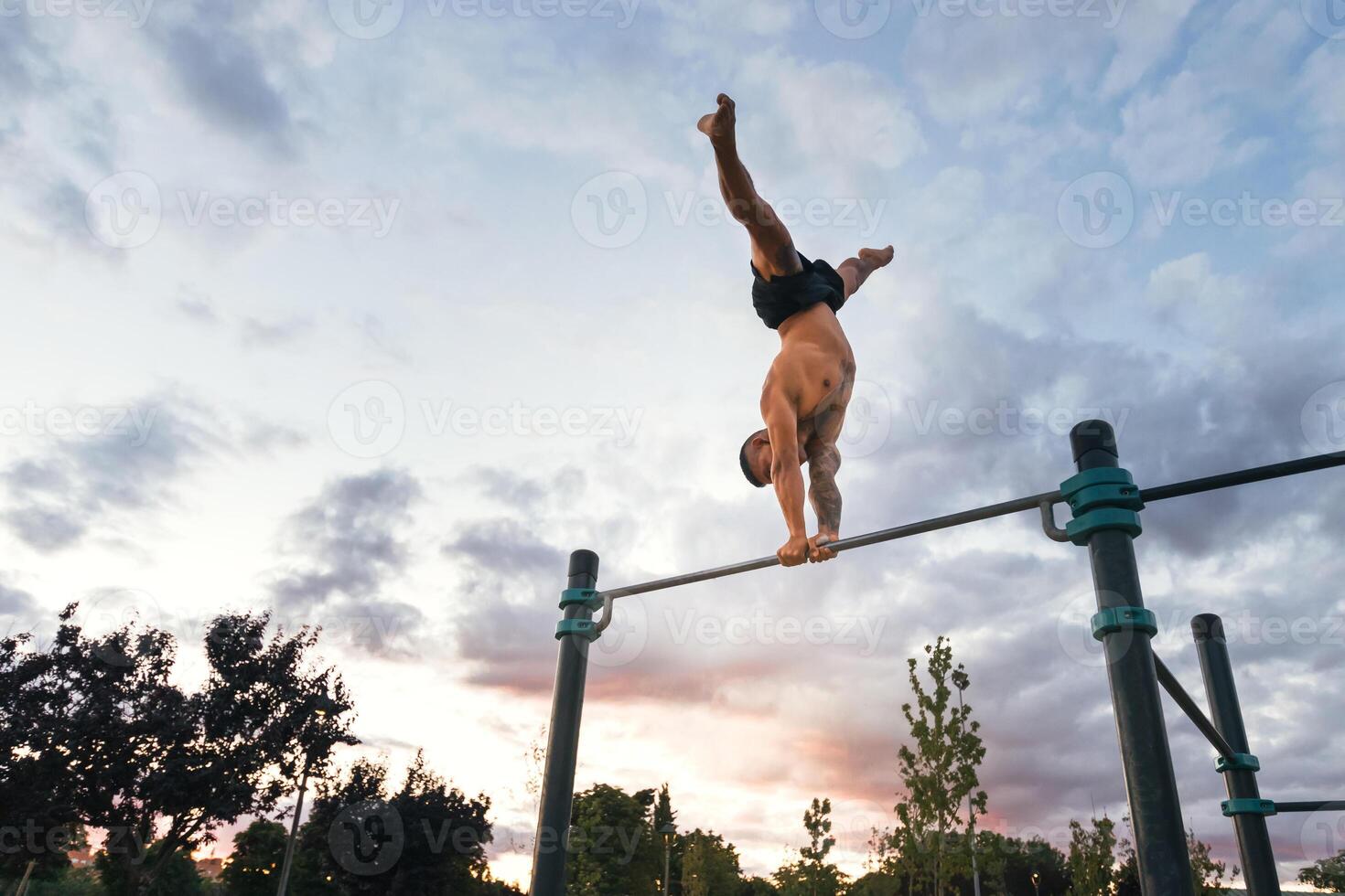 male athlete doing handstand on a bar in a calisthenic park photo