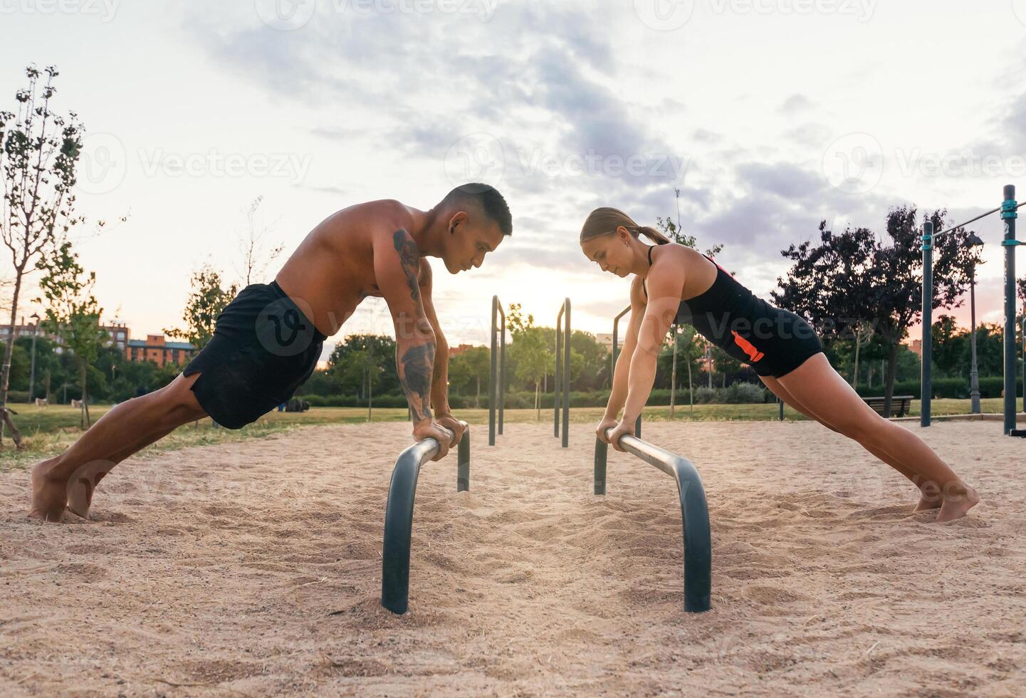 couple doing push ups on a bar in a calisthenic park photo
