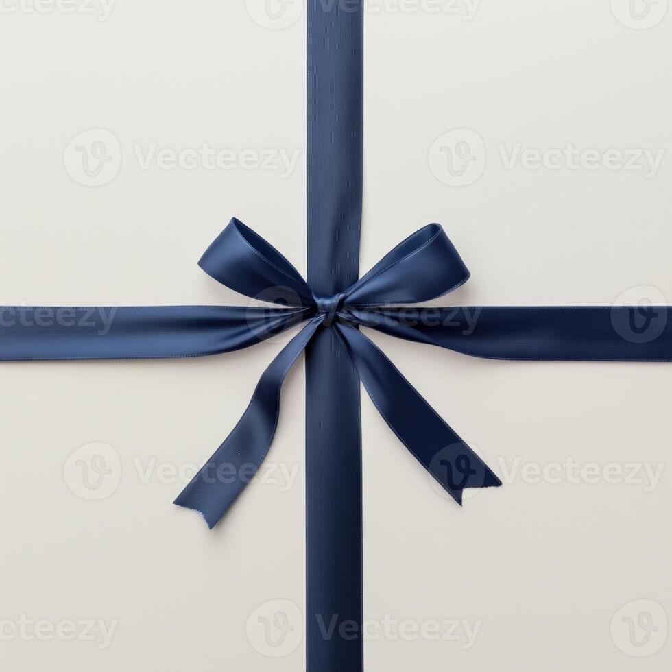 A navy blue ribbon tied in a bow on a light cream background, forming a cross pattern. photo