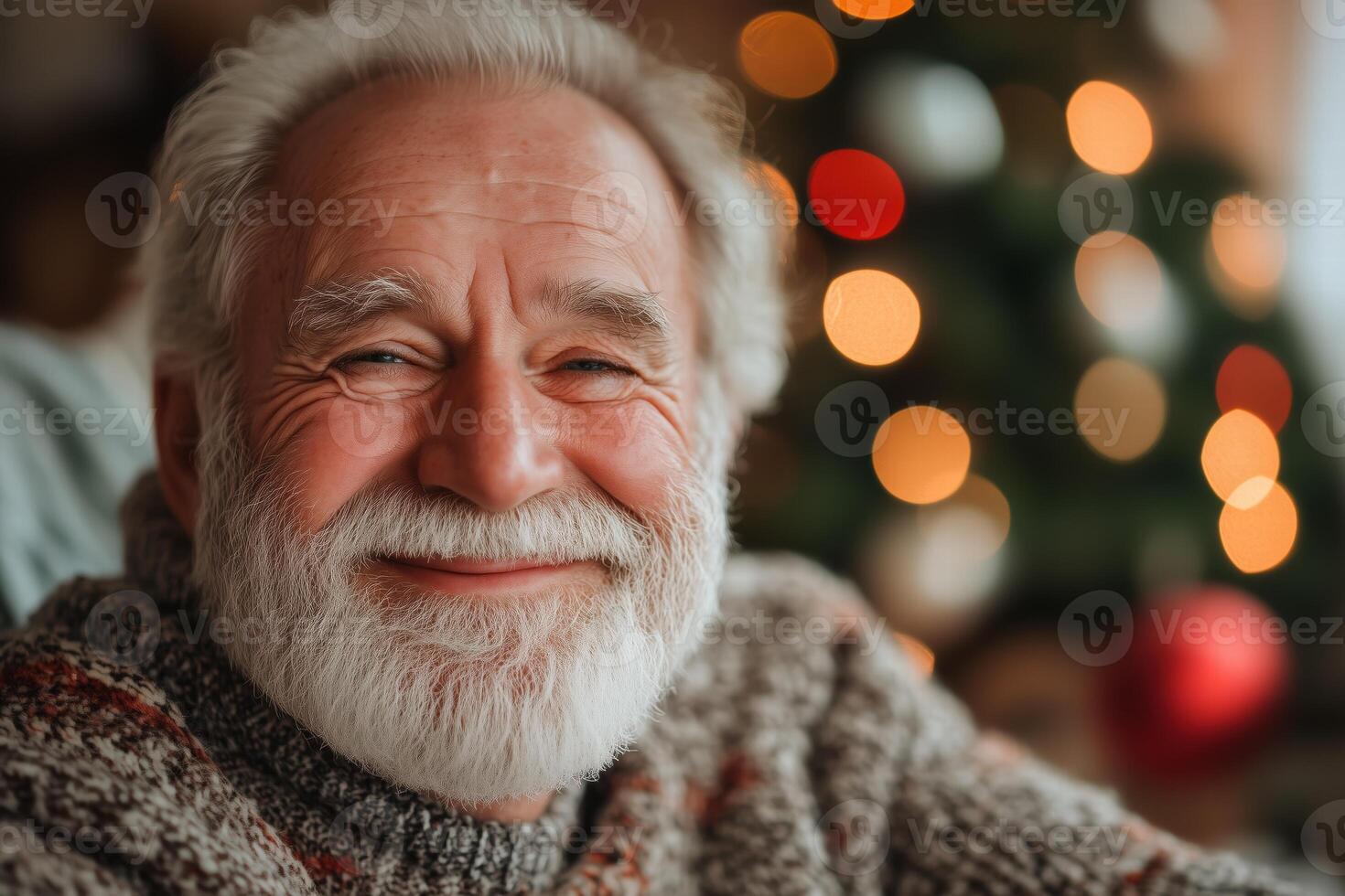 A smiling older man with a beard and a christmas tree in the background photo