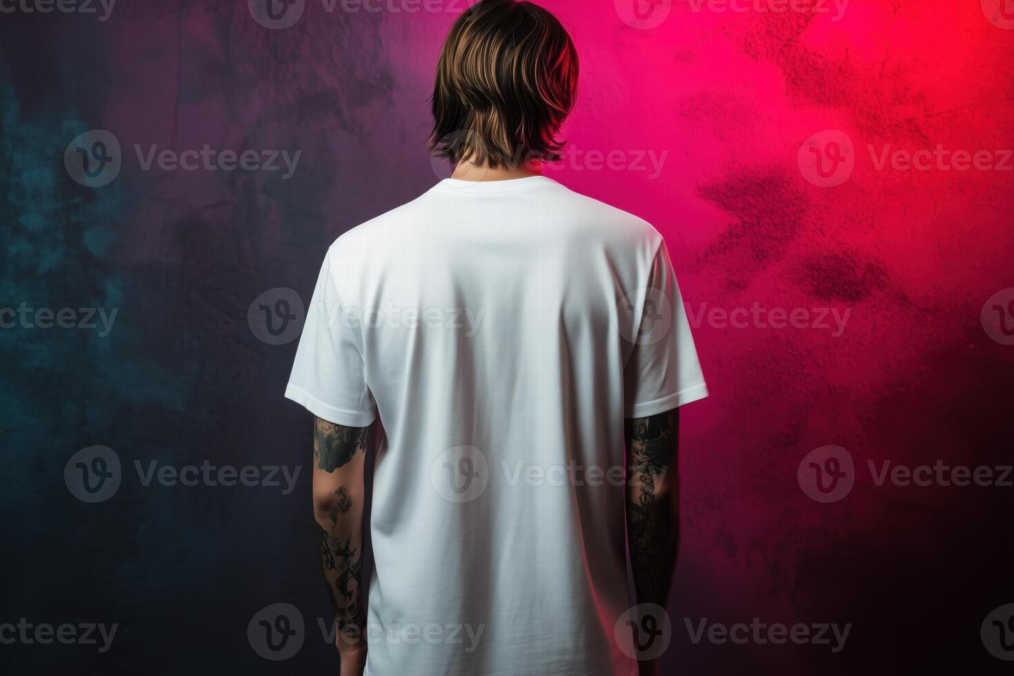 A man in a white t - shirt standing in front of a colorful wall photo