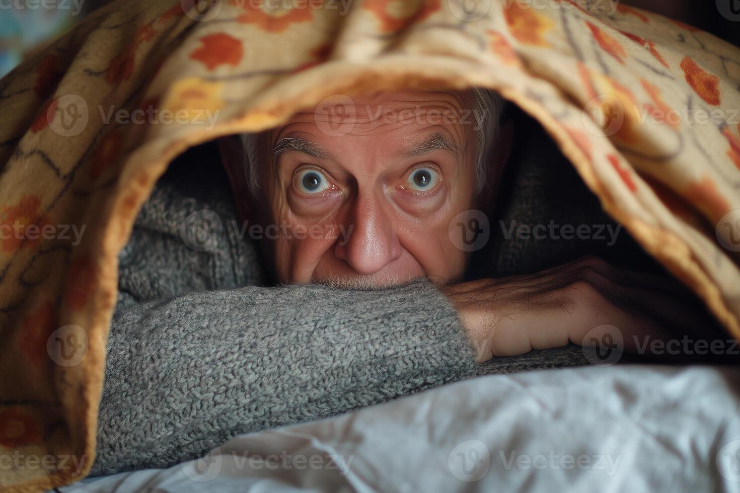 An older man is hiding under a blanket photo