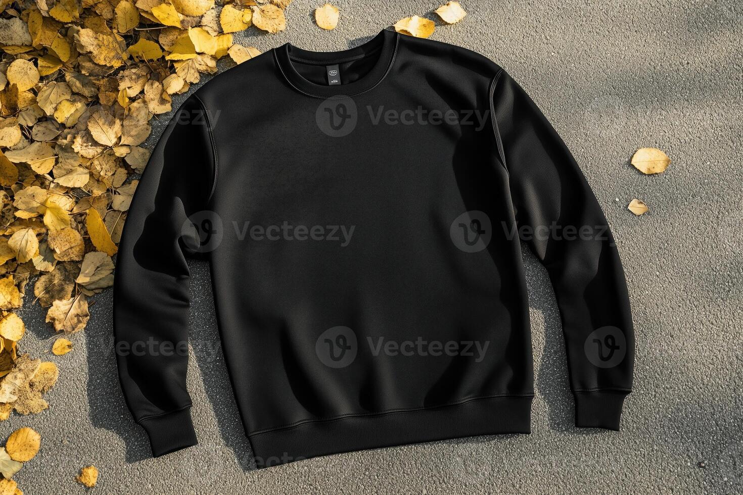 A black sweatshirt mockup laid flat on a textured surface, surrounded by autumn leaves. The sweatshirt features a classic design with a round neckline and long sleeves, ideal for casual wear. photo