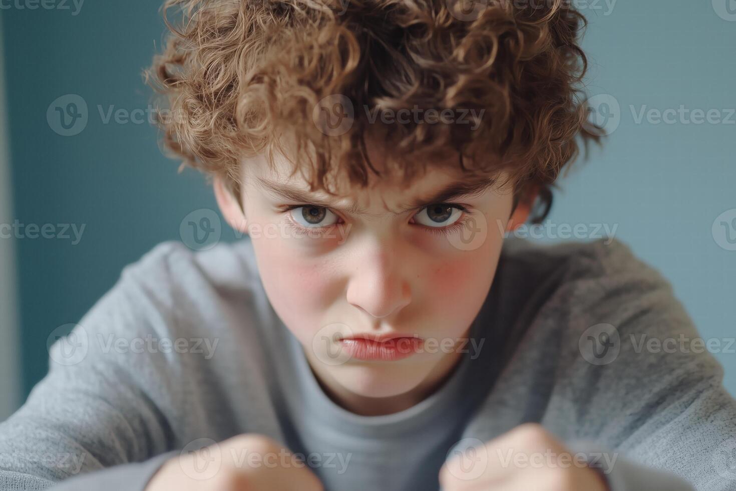 A boy with curly hair is looking at the camera photo